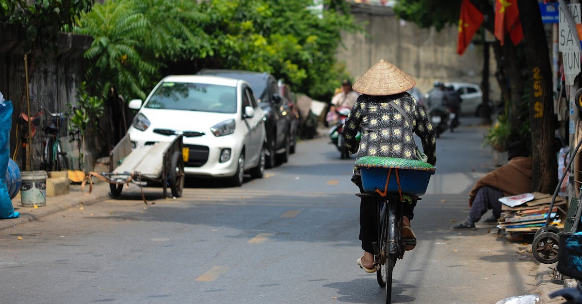 Woman on bicycle in Vietnamese street with conical hat, vibrant urban life.