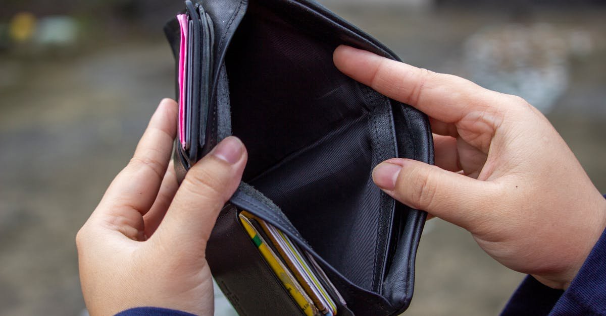 An outdoor image of hands holding an empty black wallet, suggesting financial scarcity.