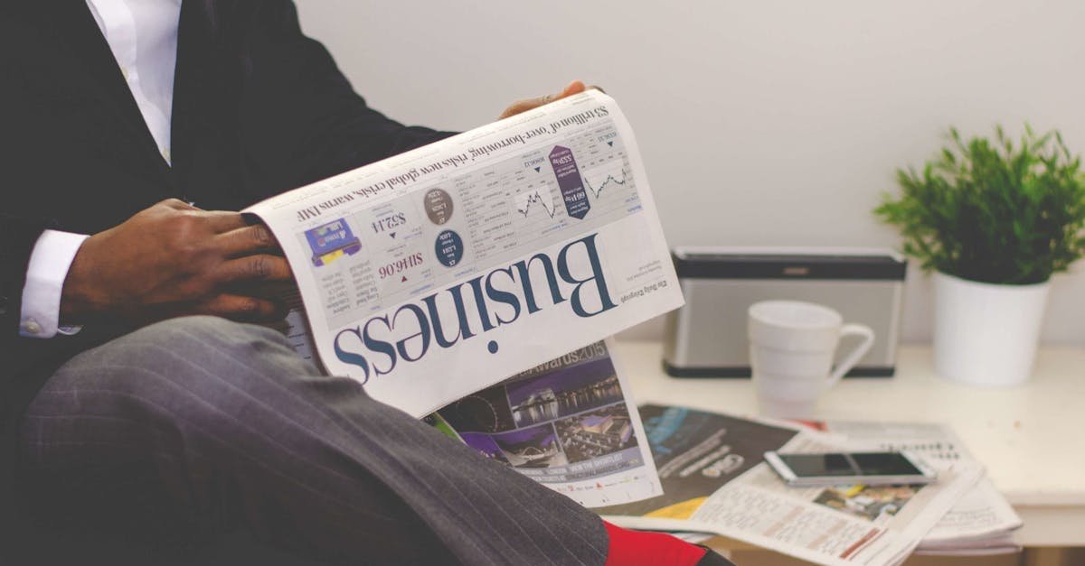 Businessman reading a financial newspaper at a desk, highlighting finance and commerce theme.