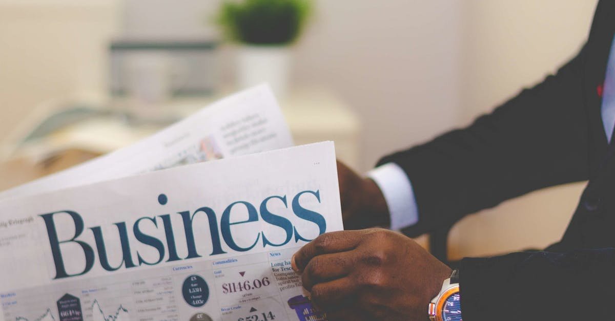 Close-up of a businessman reading a newspaper indoors, focusing on business headlines.