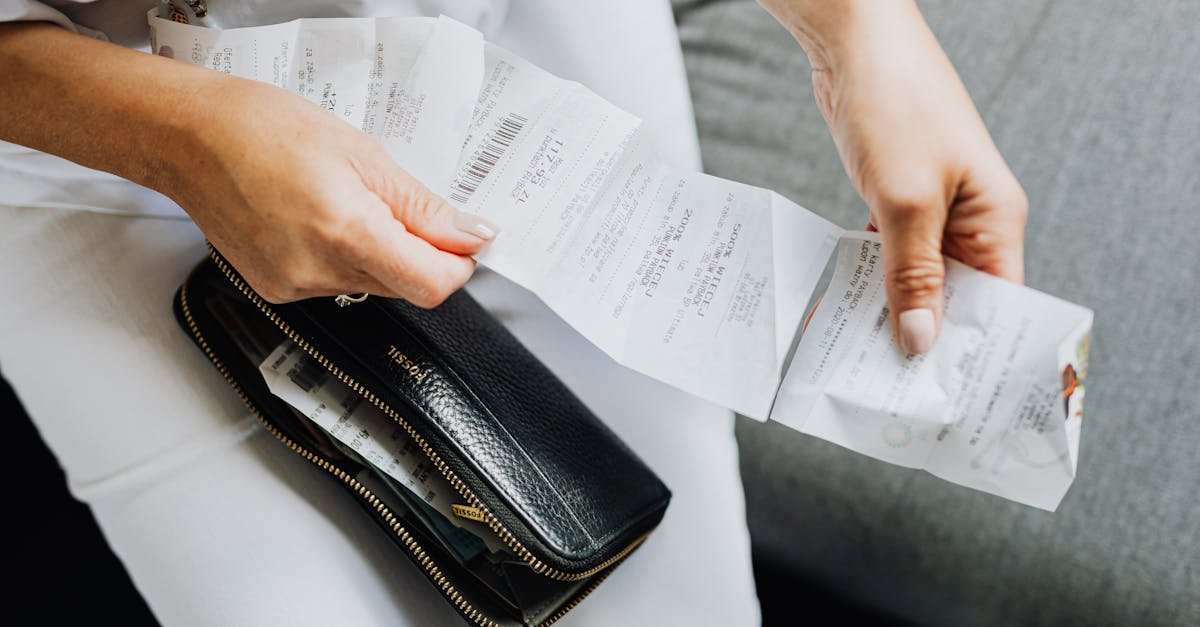 Close-up of a woman's hands managing multiple receipts taken from a black wallet.